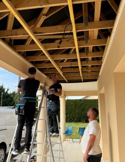 Travaux en cours : Structure en bois d'un plafond extérieur avant installation du PVC, avec artisans de SNMultiservices