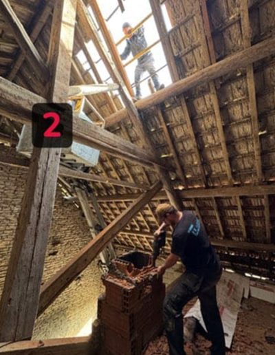 Travaux de rénovation de cheminée en cours à l'intérieur d'une maison, avec un artisan travaillant sur les briques